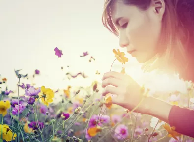 Junge Frau riecht an Blumen